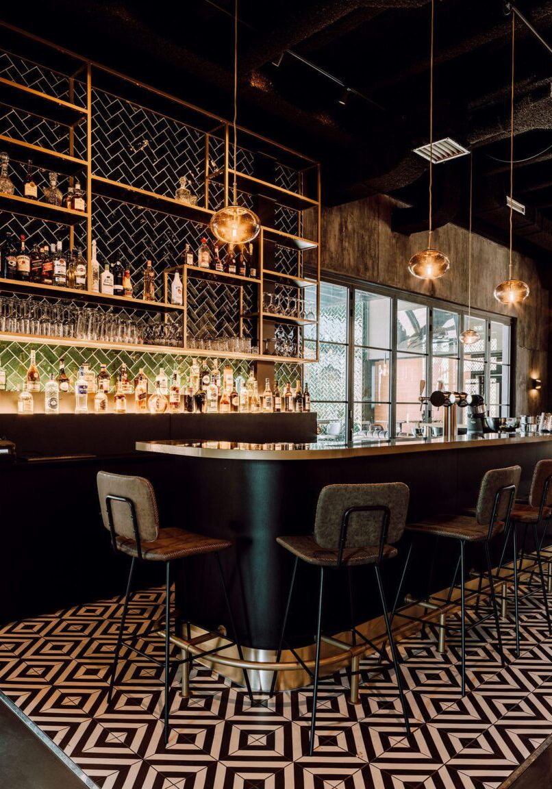 Bar in Gasterij De Patron Twello met groene herringbonetegels, gouden stellingen en geometrische vloer — maatwerk interieurbouw Mint