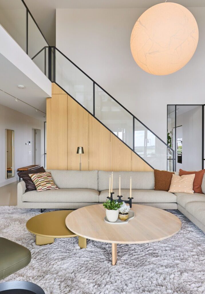 Woonkamer loft appartement met inbouwkast onder de trap in eiken en glazen vide-balustrade