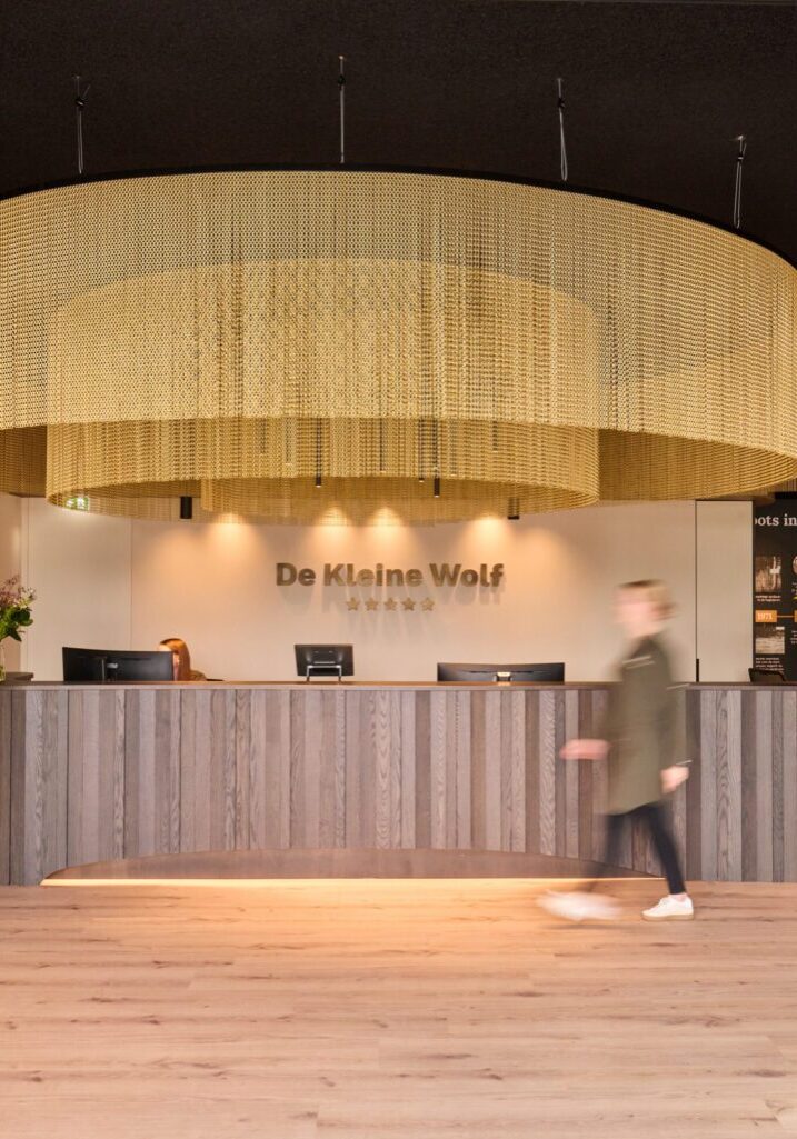 Receptiebalie met gebeitst eikenhout en rond gouden gordijn in de receptie van Camping De Kleine Wolf in Stegeren, ontwerp en realisatie door Mint Interieur