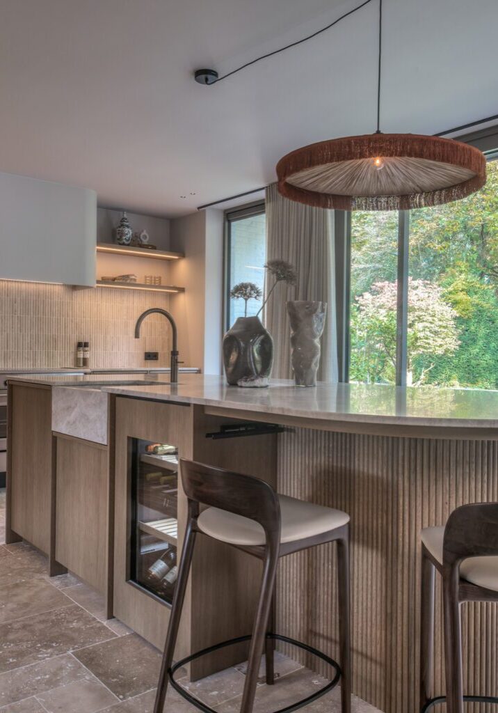Maatwerk keuken met eikenfineer kastwerk, rond keukeneiland met natuursteen werkblad en ingebouwde wijnklimaatkast