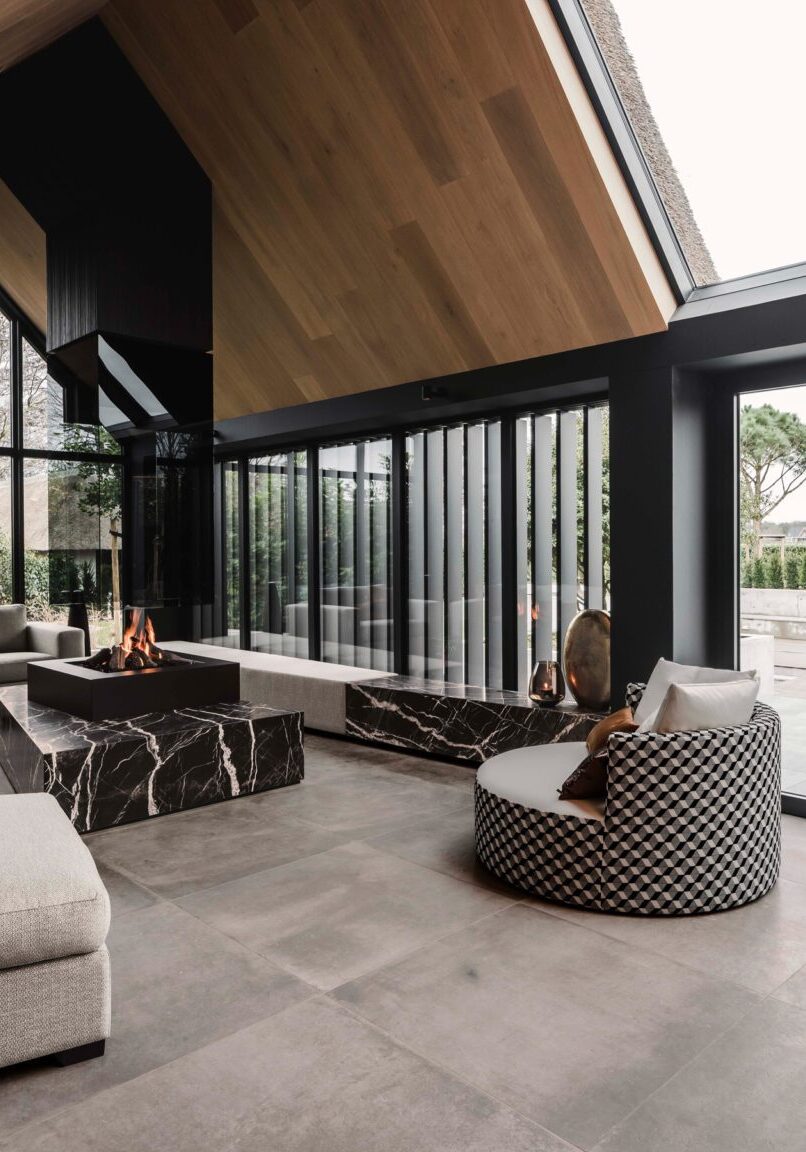 Poolhouse interieur met marmeren vuurtafel, zwart eikenhouten wandbekleding en glasgevel met zicht op het zwembad